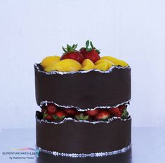 a triple layer chocolate cake with strawberries and lemons on top