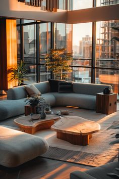 a living room filled with furniture and large windows overlooking the cityscape at sunset