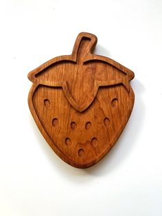 a wooden cutting board with holes in the shape of a strawberry