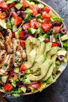 a salad with chicken, lettuce, tomatoes, cucumber and olives