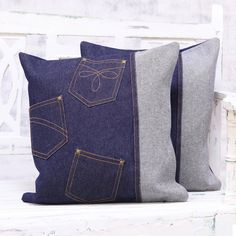 two denim pillows sitting on top of a white bench