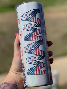 a woman's hand holding an aluminum can with patriotic designs on it