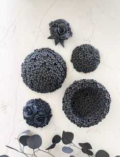 four pieces of art made out of black buttons and flowers on a white table top