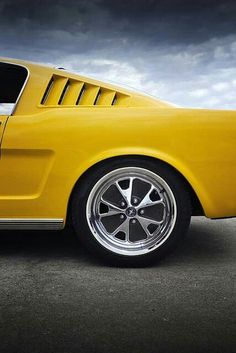 the front end of a yellow car with chrome rims