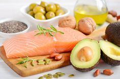 raw salmon, avocado, nuts and olives on a cutting board