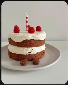 a cake with white frosting and raspberries on top, sitting on a plate