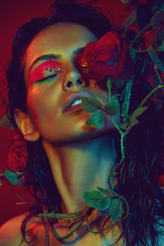 a woman with red makeup and roses on her face is posing for a photo in front of a red background