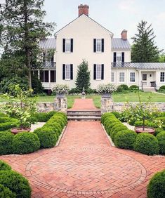 a large white house sitting next to a lush green park filled with lots of trees