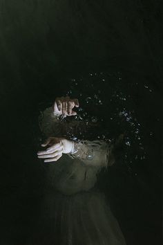 a person floating in the water with their hands up