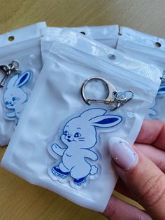 a person holding two plastic bags with keychains on them, one in the shape of a rabbit