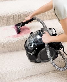 a woman using a vacuum to clean stairs