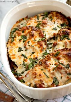 a casserole dish with cheese and spinach in it on a towel next to utensils