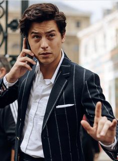 a man in a suit is talking on his cell phone and pointing to the side