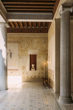 an empty room with columns and paintings on the walls