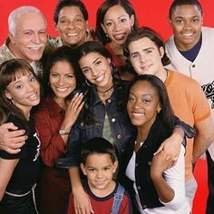 a group of people are posing for a photo with their arms around each other in front of a red background