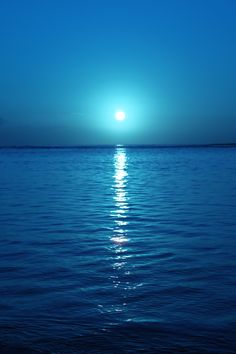 the sun is setting over the ocean with calm water and blue sky in the background