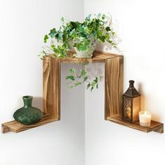 two wooden shelves with plants on them and candles in the corner next to each other