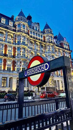 the underground sign is lit up in front of a large building with many windows on it