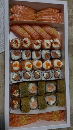 an assortment of sushi in a white box