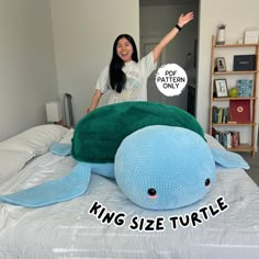 a woman standing next to a stuffed turtle on top of a bed with the caption king size turtle