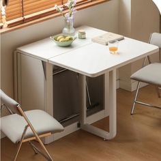 a white table with two chairs and a bowl of fruit on the table next to it