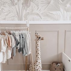 a giraffe is standing next to clothes hanging on a rack in front of a wall