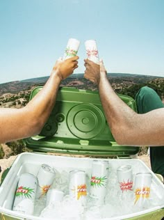 two men are holding their hands over an ice chest with six empty cans in it