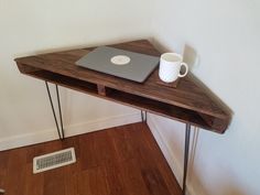 a laptop computer sitting on top of a wooden desk next to a white cup and radiator