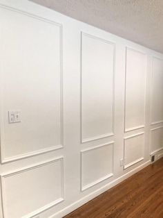 an empty room with white paneling and wood floors