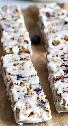 blueberry granola bars are lined up on a piece of parchment paper with white icing