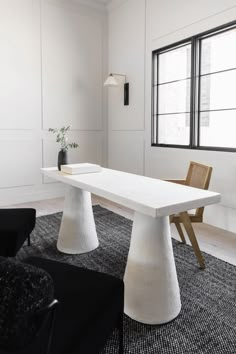 a large white table sitting in the middle of a living room next to a window