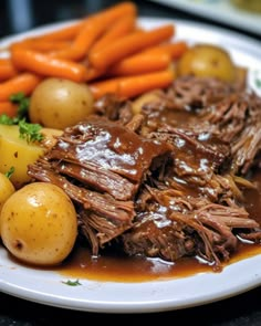 a white plate topped with meat, potatoes and carrots next to gravy