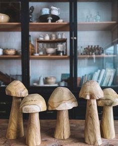 three wooden mushrooms sitting on top of a table next to a book shelf filled with books