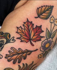 a woman's arm with tattoos on it that include leaves, flowers and an owl