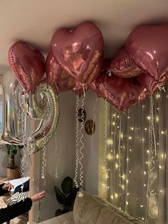 some balloons are hanging from the ceiling in front of a couch and window with lights