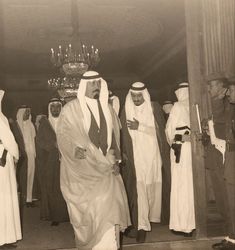 a group of men standing next to each other in front of a chandelier