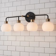 a bathroom light with four lights on it and white brick wall in the back ground