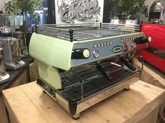 an espresso machine sitting on top of a wooden table next to other coffee machines