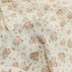 an unmade bedspread with pink flowers on it