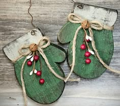 two green christmas mitts with red berries hanging from twine on wooden planks