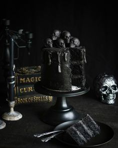 a black cake with skulls on it and a book next to it, in the dark