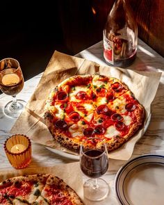 a pizza sitting on top of a table next to wine glasses