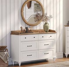 a white dresser and mirror in a room with wood paneling on the wall behind it