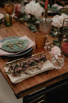 a wooden table topped with plates and flowers