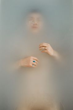 two hands in the water with rings on their fingers and one hand holding something blue