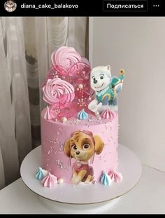 there is a pink cake decorated with dogs and candy on the top, as well as other decorations