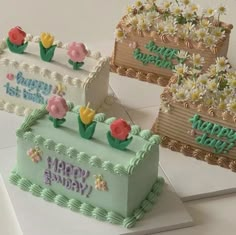 three cakes decorated with flowers and the words happy birthday written on them are sitting next to each other