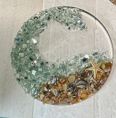 a glass bowl filled with sea shells and starfish on top of a white table