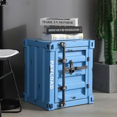 a stack of books sitting on top of a blue box next to a chair and table