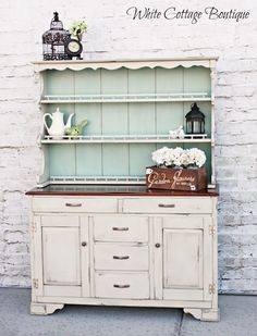 an old china cabinet with flowers and teapots on top is painted aqua blue